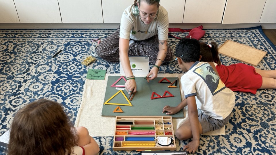 Montessori guide teaching geometry with triangle materials on a rug