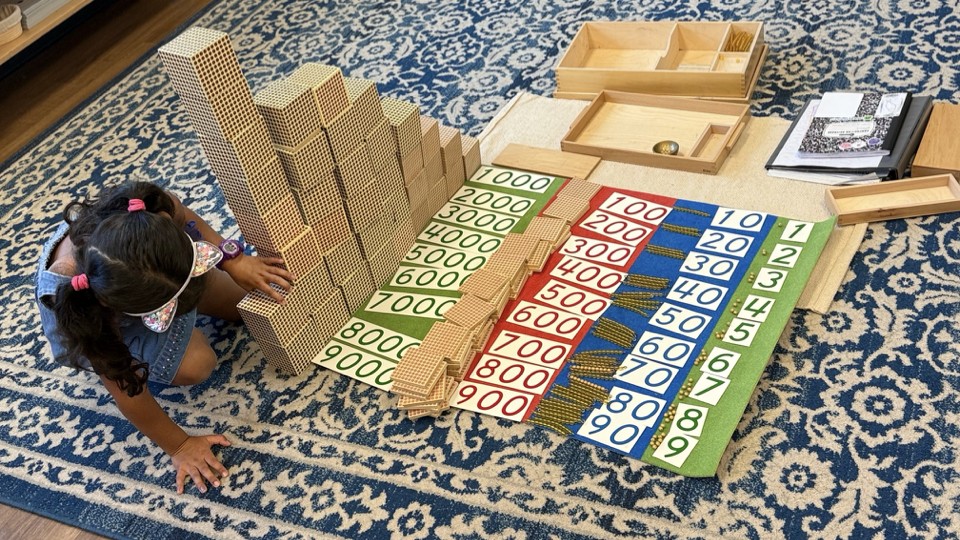 Student building with golden bead decimal system materials