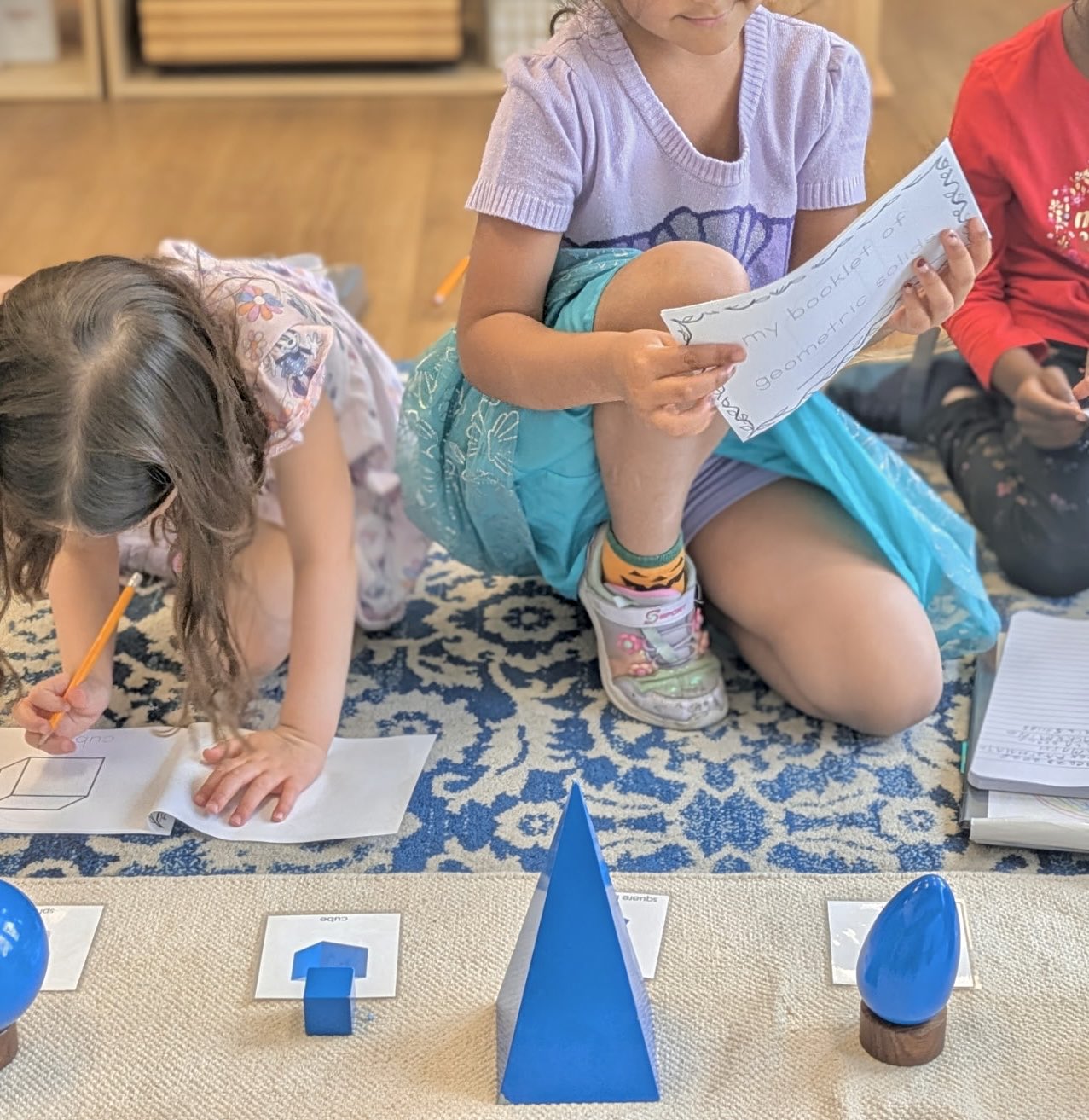 Students studying geometric solids and writing in their booklets